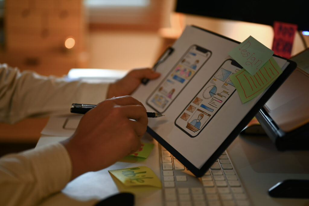 Creative designer working on development project for mobile application at dark office.