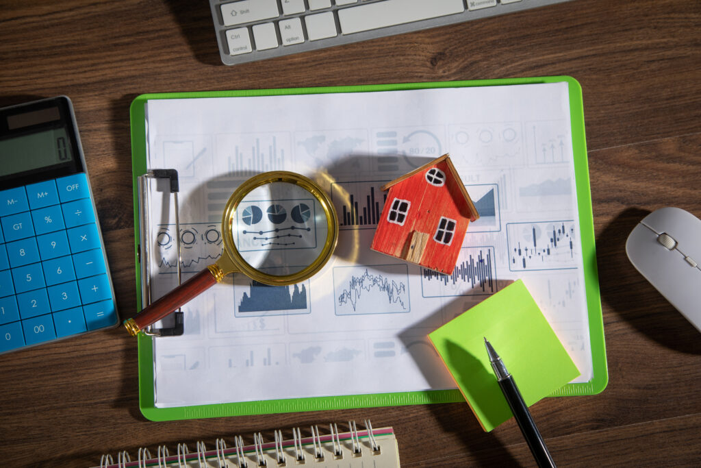 House model, graphs, magnifying glass with a business objects on the table.
