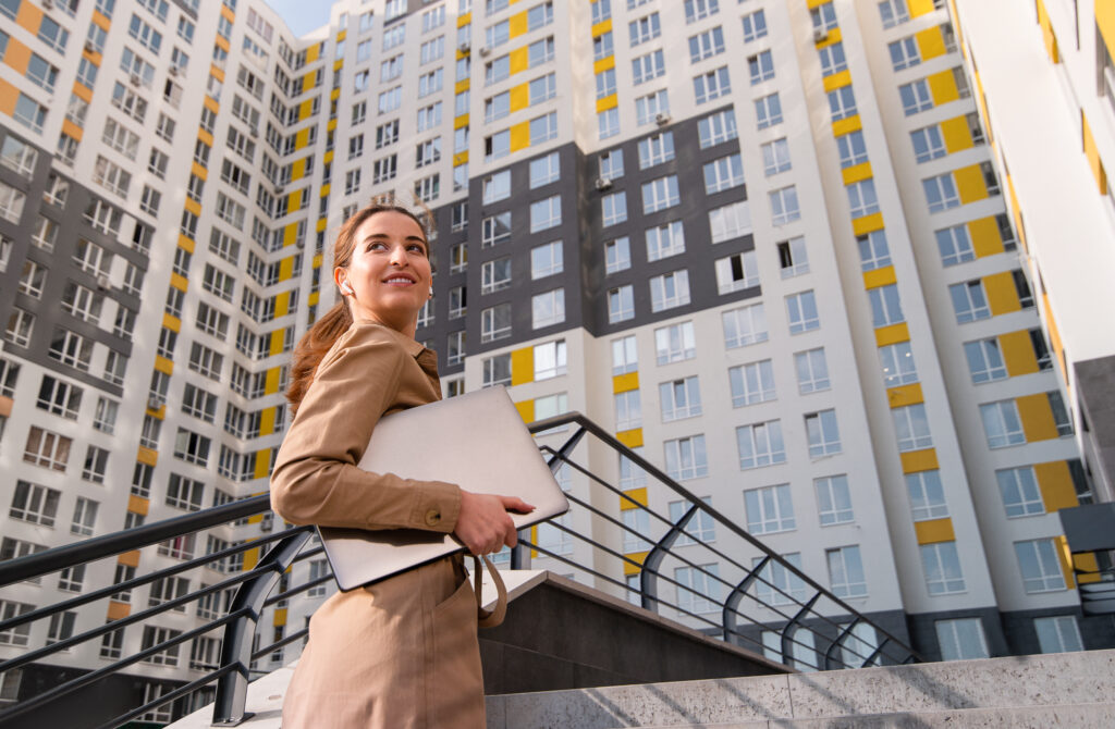 Young successful business woman looks over her shoulder and smiles while climbimg the stairs of a high-rise buiding